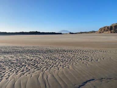 A beach with sand patterns and distant mountain at Geesala