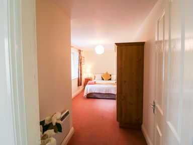 A bedroom with a bed bedside table lamp wardrobe and window with curtains at 2 Garnish Court in Glengarriff County Cork