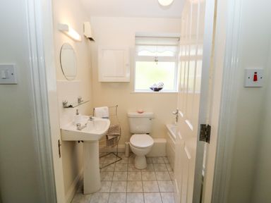 A bathroom with a pedestal sink a toilet a window and a towel rack at 2 Garnish Court in Glengarriff County Cork