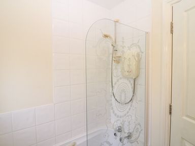 A bathroom with a bathtub shower unit and a decorative glass screen at 2 Garnish Court in Glengarriff County Cork