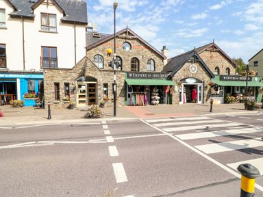 A street view with stone buildings housing Weavers of Ireland shops and a blue bistro at 2 Garnish Court in Glengarriff County Cork