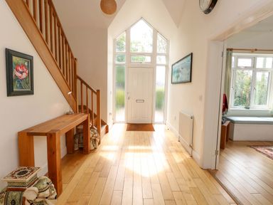 A hallway with a staircase and a console table at 1 Fernhill Avenue in Weymouth