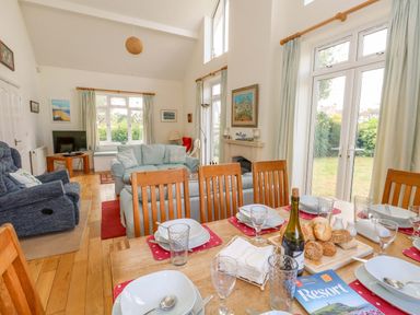 A dining room with a table set and a living area at 1 Fernhill Avenue Weymouth