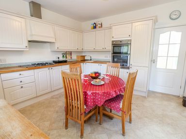 A kitchen with a dining table and appliances at 1 Fernhill Avenue Weymouth