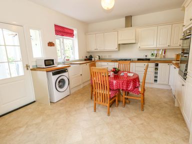 A kitchen with a table and chairs at 1 Fernhill Avenue in Weymouth