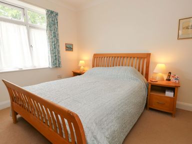 A bedroom with a wooden bed and nightstand at 1 Fernhill Avenue in Weymouth