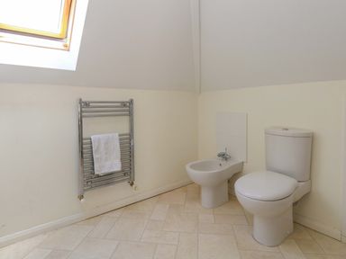 A bathroom with a toilet, bidet, towel rail, and window at 1 Fernhill Avenue in Weymouth