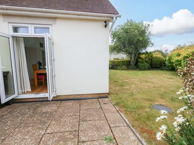 A garden view from a patio with doors open at 1 Fernhill Avenue Weymouth