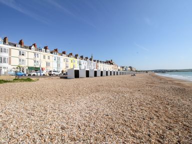 A seaside view with houses and beach huts at 1 Fernhill Avenue Weymouth