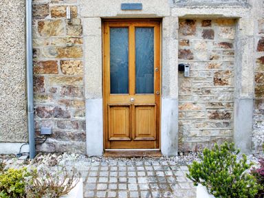 A wooden door set in a stone wall with plants on either side at The Tower 5 Corisande Manor Newquay