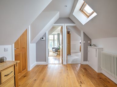 A hallway with wooden floor and doors leading to a living room and another room at The Tower 5 Corisande Manor in Newquay