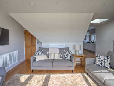 A living room with two gray sofas cushions a side table and a lamp at The Tower 5 Corisande Manor in Newquay