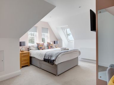 A bedroom with a double bed between two windows and a skylight at The Tower 5 Corisande Manor in Newquay