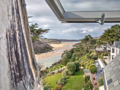 A coastal view of a garden with trees bushes and a sandy beach beyond at The Tower 5 Corisande Manor in Newquay