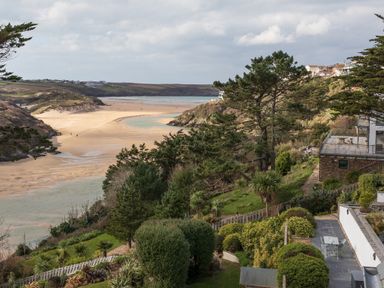 A coastal landscape with a sandy beach a river mouth trees and residential buildings at The Tower 5 Corisande Manor in Newquay