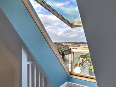 A skylight window overlooking a beach and coastal landscape at The Tower 5 Corisande Manor in Newquay