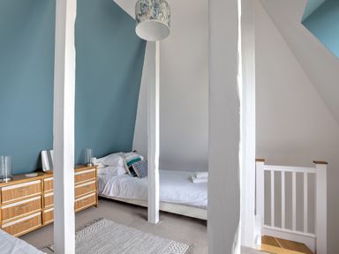 A bedroom with a single bed a dresser with two lamps and a rug on the floor at The Tower 5 Corisande Manor in Newquay