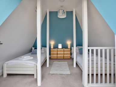 A bedroom with two single beds separated by white beams and a dresser with lamps at The Tower 5 Corisande Manor in Newquay