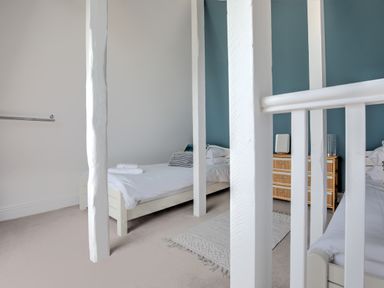 A bedroom with two single beds a wooden dresser a mirror and white beams at The Tower 5 Corisande Manor in Newquay