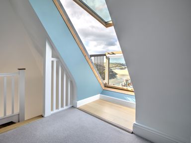 An attic room with a slanted skylight window and a stair railing at The Tower 5 Corisande Manor in Newquay