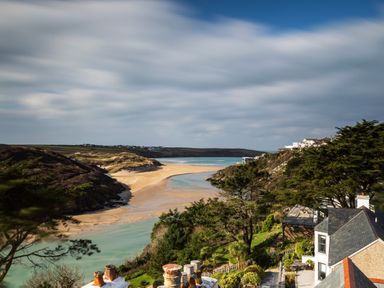 A coastal landscape with sandy beach water and houses on cliffs at The Tower 5 Corisande Manor in Newquay