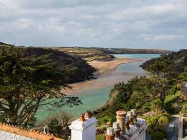 A coastal landscape with a river flowing into the sea and houses on a hillside at The Tower 5 Corisande Manor in Newquay