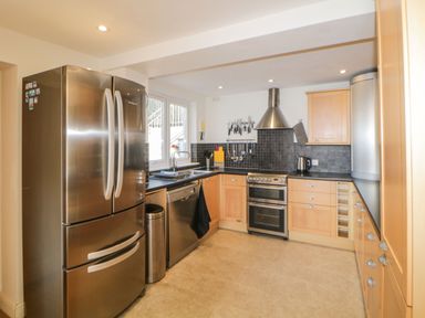A kitchen with stainless steel refrigerator dishwasher oven and wooden cabinets at Estuary View in Newton Ferrers