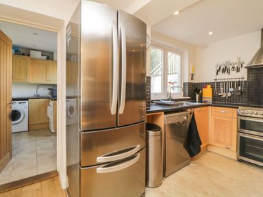A kitchen with stainless steel refrigerator dishwasher and oven with utensils hanging on the wall at Estuary View in Newton Ferrers