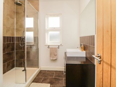 A bathroom with a shower enclosure a sink with a vanity unit and a window at Estuary View in Newton Ferrers