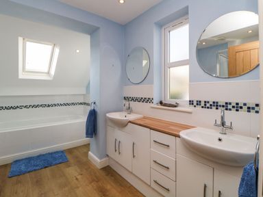A bathroom with two sinks mirrors a bathtub and a skylight at Estuary View in Newton Ferrers