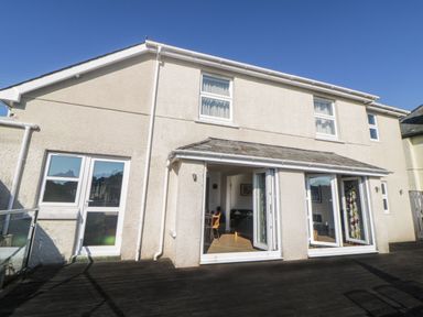 The exterior of a two story house with glass doors opening onto a wooden deck at Estuary View in Newton Ferrers
