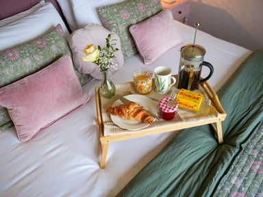 A breakfast tray with a croissant and drinks on a bed at Dol Blodau in Newbridge-On-Wye