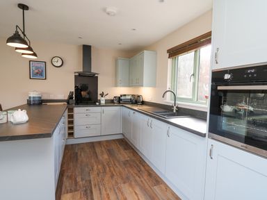 A kitchen with light blue cabinets black countertops a window and built in oven at Ystrad Wen in Llysdinam near Newbridge-On-Wye