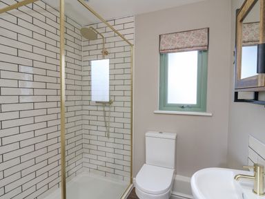 A bathroom with a walk-in shower with glass door a toilet a window with a blind and a sink with a faucet at Ystrad Wen in Llysdinam near Newbridge-On-Wye
