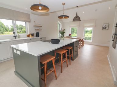 A kitchen with an island and wooden stools beside large windows at Shannon Vale in Woodford County Galway
