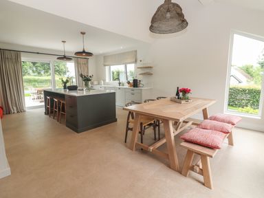 A kitchen and dining area with a wooden dining table and bench cushions at Shannon Vale in Woodford County Galway