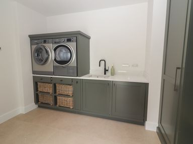 A laundry room with washing machine dryer sink and wicker baskets at Shannon Vale in Woodford County Galway