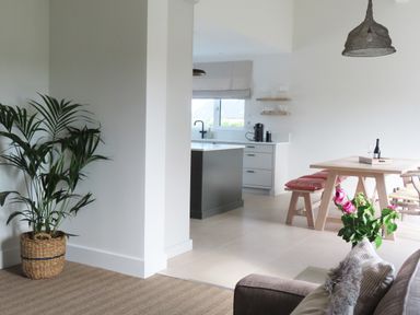 An open plan kitchen and dining area with a wooden dining table and bench sitting with cushions and a potted plant in the corner at Shannon Vale in Woodford County Galway