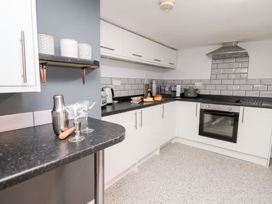 A kitchen with white cabinets black countertops and a tiled backsplash at Lane Cottage in Cardigan