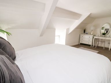 A bedroom with a bed white dresser and vanity with mirror at Lane Cottage in Cardigan