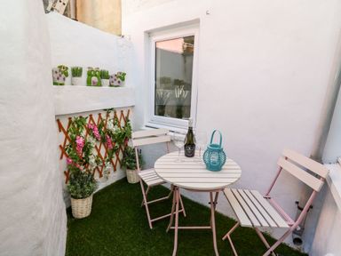 A small outdoor patio with two chairs a round table a bottle of wine wine glasses plants and decorative items at Lane Cottage in Cardigan