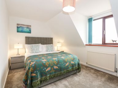A bedroom with a bed bedside tables lamps a window and a radiator at Harveys Holiday House in Hunstanton
