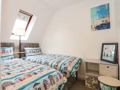 A bedroom with two single beds with patterned bedding under a skylight window at Harveys Holiday House in Hunstanton