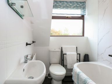 A bathroom with a sink a toilet a towel rack and a bathtub at Harveys Holiday House in Hunstanton