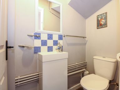 A bathroom with a toilet sink mirror and a wall sign at Harveys Holiday House in Hunstanton