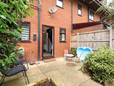 A small patio area with chairs a table and plants outside a brick house at Harveys Holiday House in Hunstanton