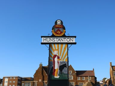 A sign with a crowned figure and a black dog under the text Hunstanton in an outdoor setting at Harveys Holiday House in Hunstanton
