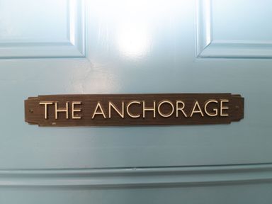 A black plaque with the text the anchorage attached to a blue door at The Anchorage in Bournemouth