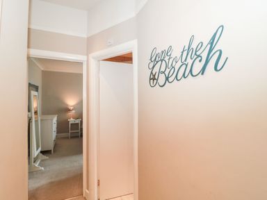A hallway with two doorways and a wall decoration saying gone to the beach at The Anchorage in Bournemouth