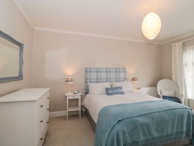 A bedroom with a double bed two bedside tables lamps a chest of drawers a chair and a window at The Anchorage in Bournemouth